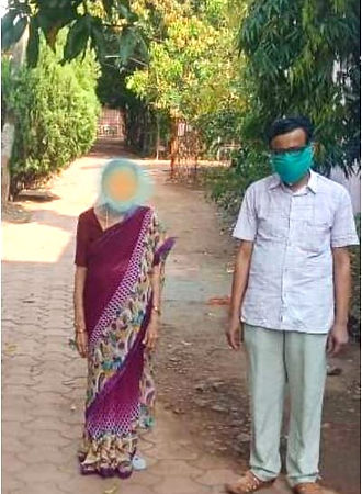 A woman, face blurred, standing outdoors with a man wearing a mask