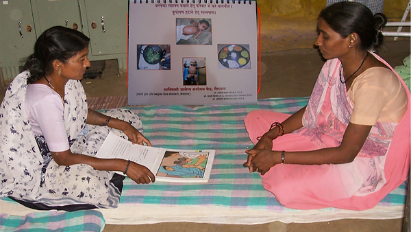 Home Based Child Care: a health worker counselling a mother with a picture booklet